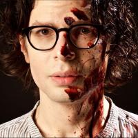 Simon Amstell with blood on his face to promote his film Carnage